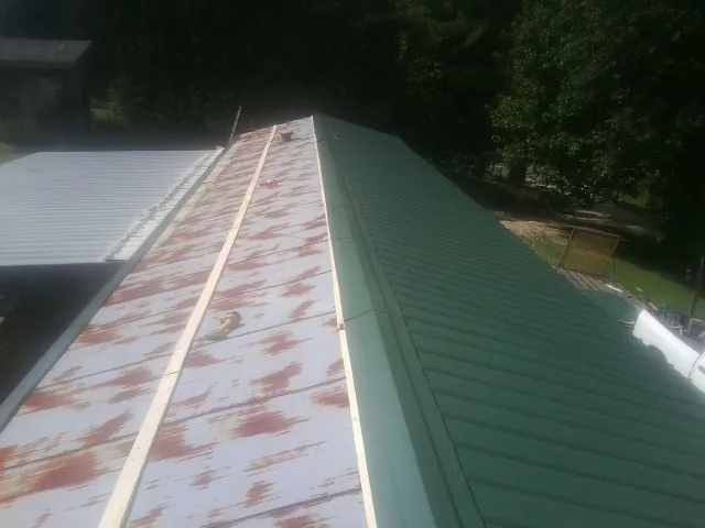 Old rusted panels beside newly installed green metal roofing — Wind Damage Roof Repair by Roofing Brothers in Rogersville